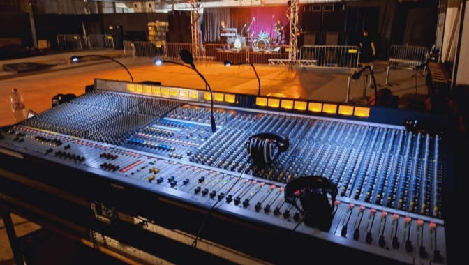 A DJ console is visible in the foreground of the image.